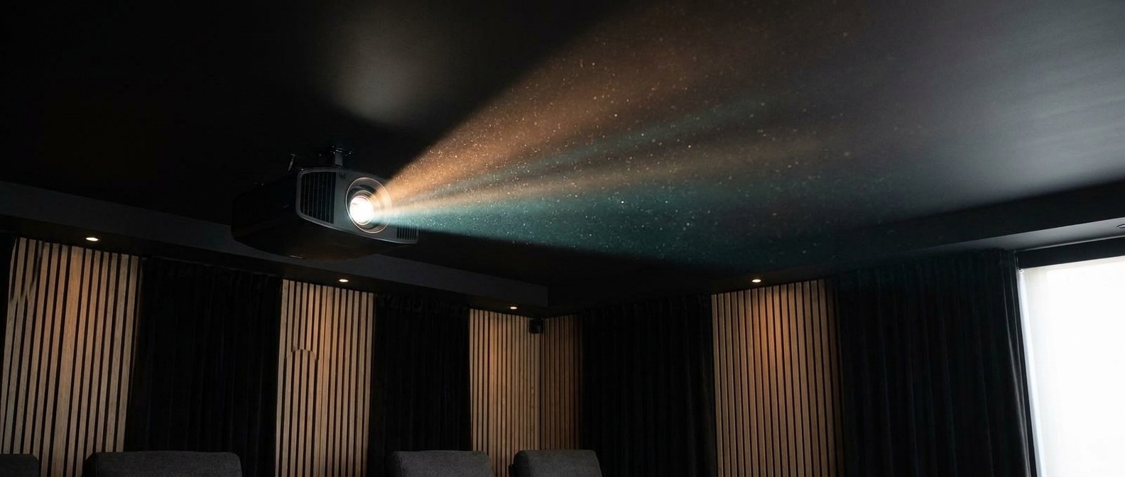 Lichtkegel des Projektors unter der Decke mit schwebendem Staub im dunklen Heimkino (Symbolbild)
